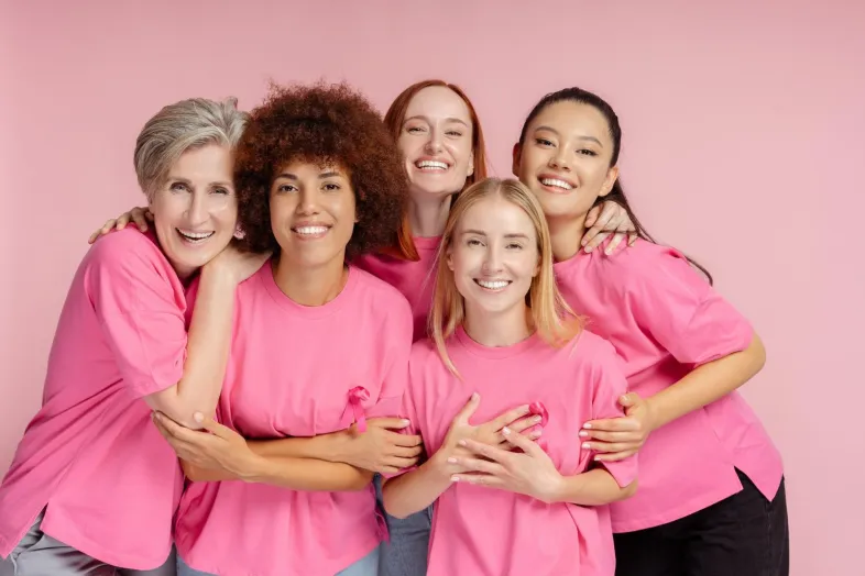 Women in pink shirts hugging.